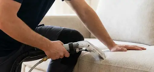 Professional upholstery cleaner deep-cleaning a fabric sofa with a handheld extraction tool, Yonkers, NY.